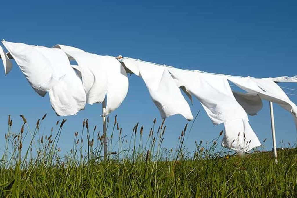 Linge suspendu a un fil dans un champ a la campagne symbolisant le soin et la simplicite des gestes d'entretien
