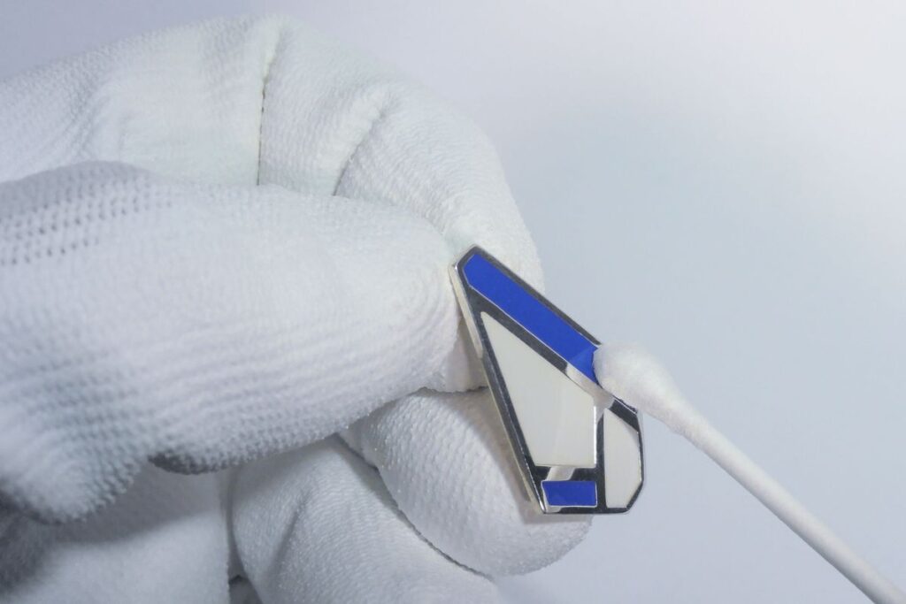 Main utilisant un coton tige pour entretien delicatement une boucle d'oreille Olpi en argent et laque