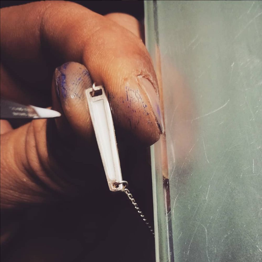 Mains d'artisan bijoutier appliquant minutieusement la laque biosourcée sur le bracelet KDA, illustrant la précision du savoir-faire Auclair-Création.